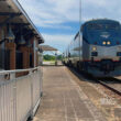 Silver and blue Amtrak train arrives at a station.